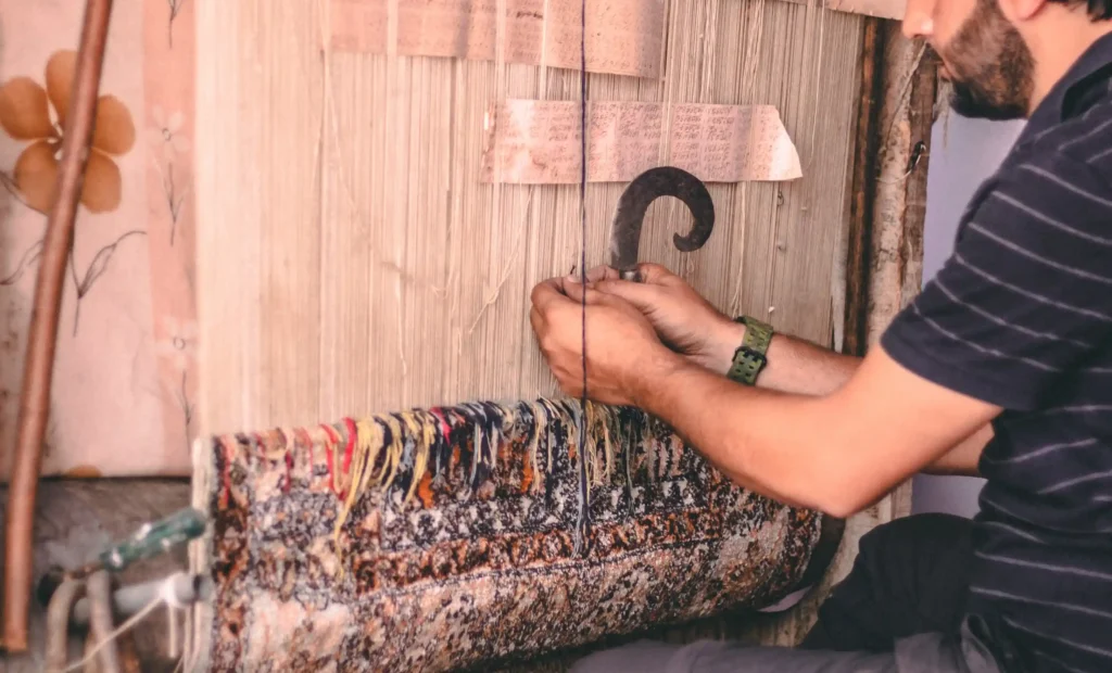 artisan weaving hand knotted silk carpet in kashmir