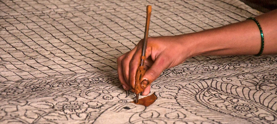 artisan making kalamkari shawl by drawing design with a pen on pashmina
