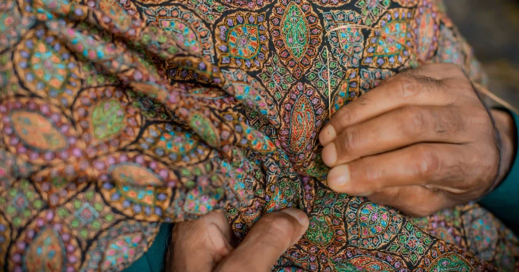 artisan doing sozni work on a black pashmina shawl in kashmir