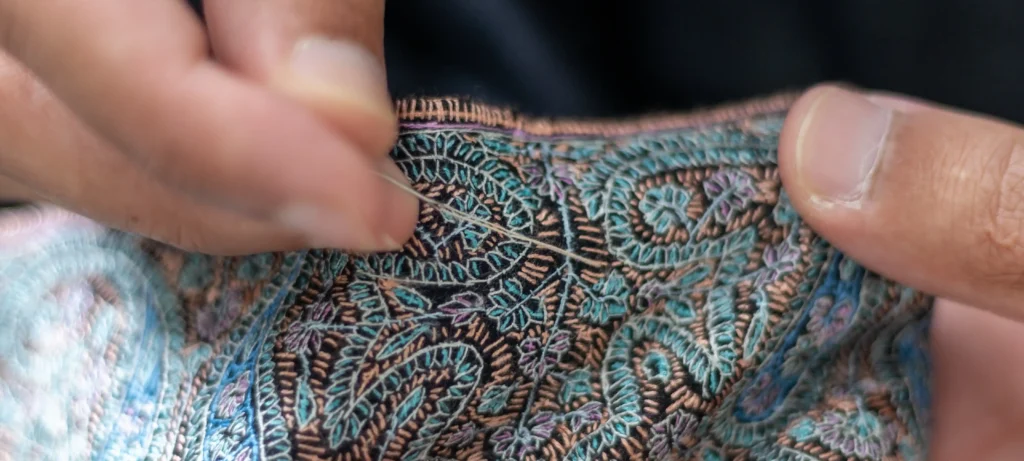 artisan doing sozni embroidery on a black pashmina shawl in kashmir
