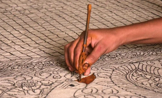 artisan making kalamkari shawl by drawing design with a pen on pashmina